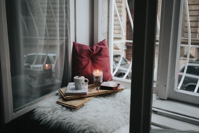 small coffee on a pillow with a candle in front of the window