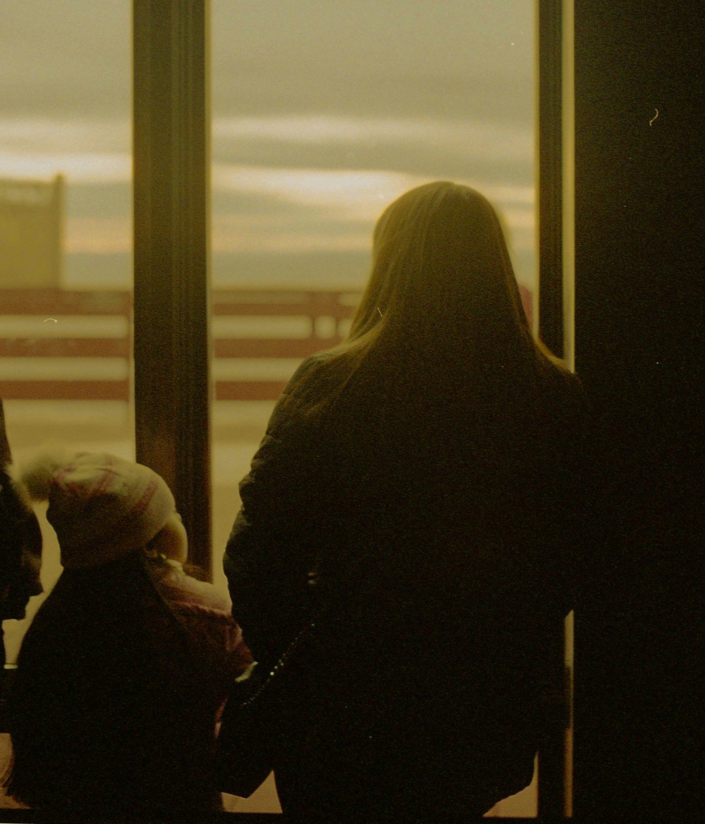 Mother and child looking out a window at sunset, symbolizing reflection, resilience, and the quiet strength of solo parenting