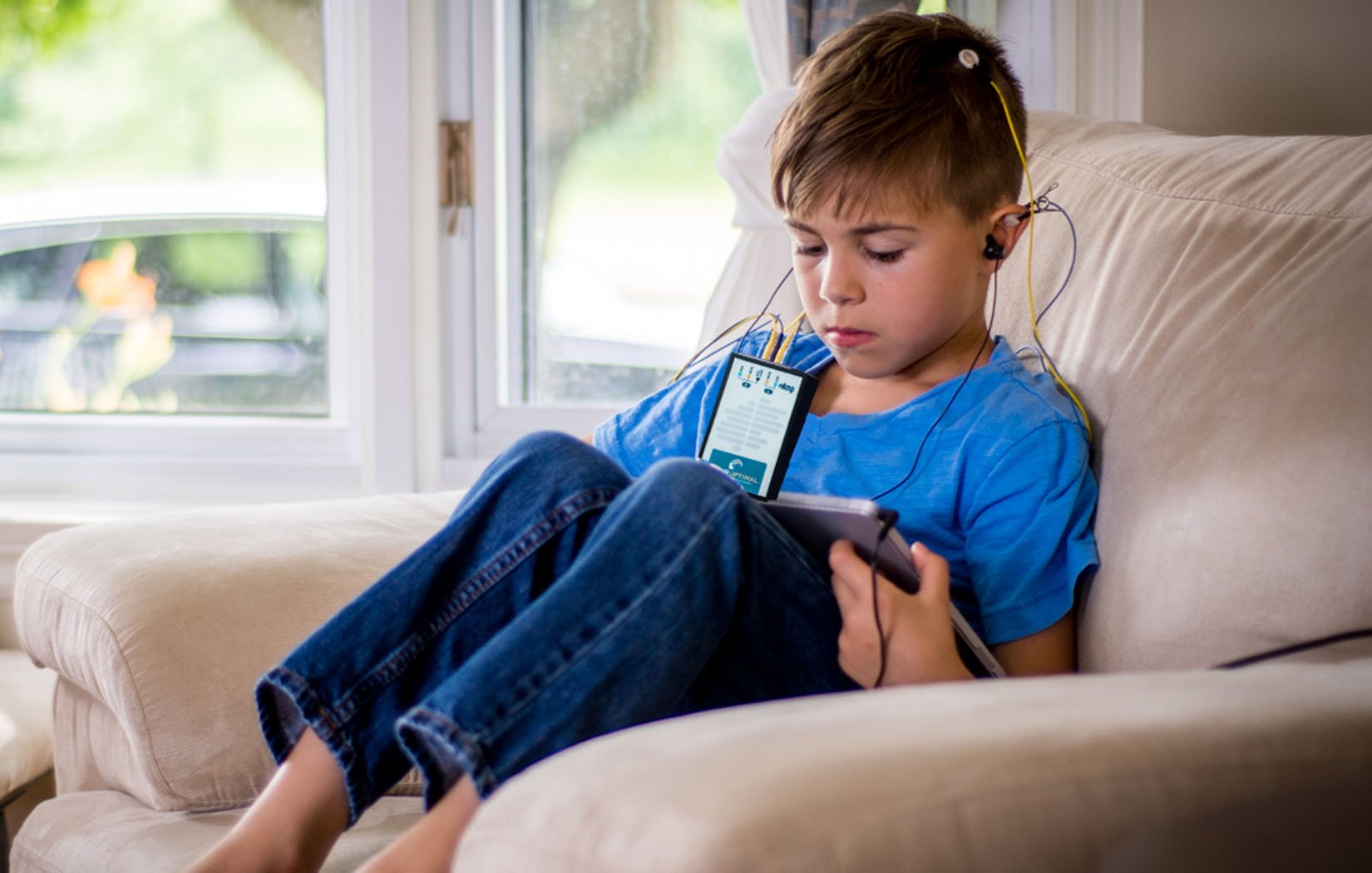 Young boy with NeurOptimal tablet running a session on couch