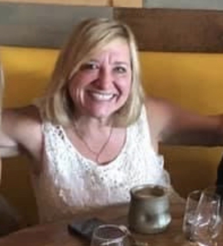 Happy woman with blonde hair raising her arms at a restaurant