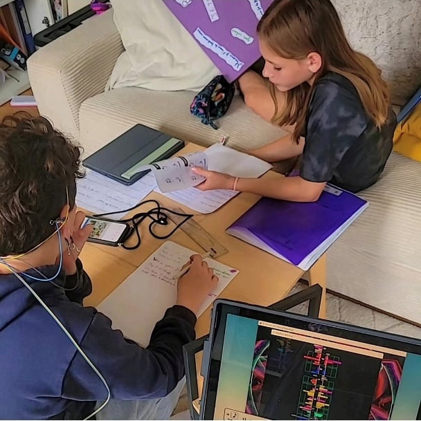 Two young students doing homework while running a NeurOptimal neurofeedback session at home