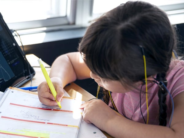 Middle school students writing in notebooks while wearing NeurOptimal neurofeedback sensors