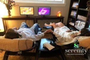 a couple holding hands using neuroptimal on seperate couches